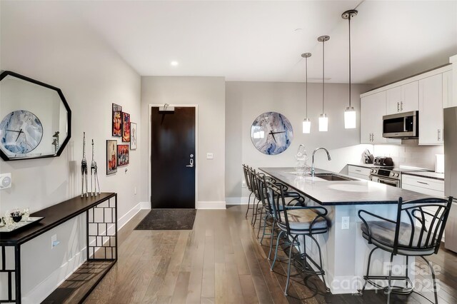 kitchen featuring a breakfast bar, dark wood-type flooring, white cabinets, a sink, and appliances with stainless steel finishes