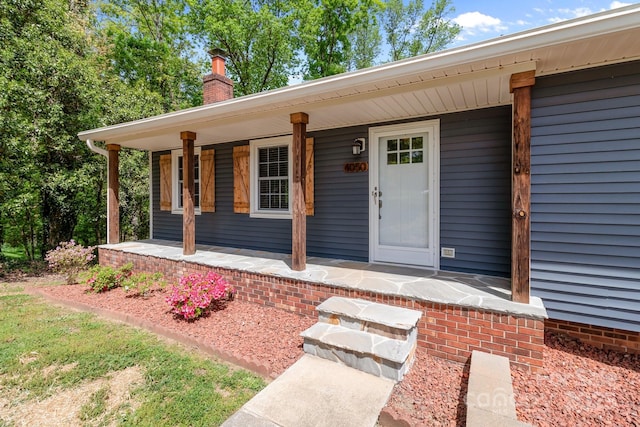doorway to property with a porch and a chimney