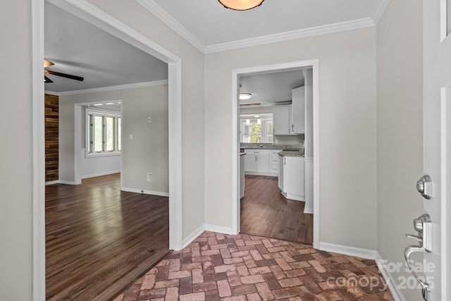 entrance foyer featuring a ceiling fan, baseboards, ornamental molding, and brick floor