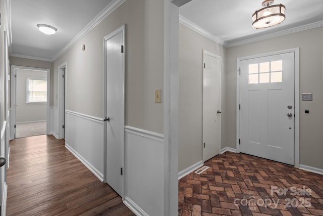 entryway featuring baseboards, ornamental molding, and visible vents