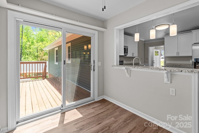 doorway to outside with baseboards, wood finished floors, and a sink