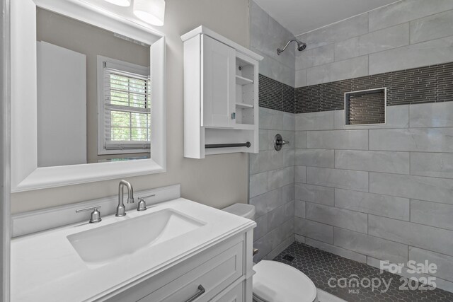 full bath featuring toilet, vanity, and a stall shower
