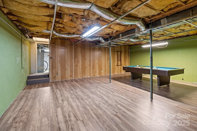 unfinished below grade area with billiards, wood finished floors, and concrete block wall