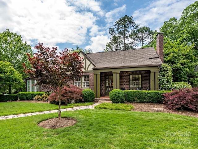 1596 Clayton Dr, Charlotte, NC 28203 - tudor-style house with covered porch, brick siding, a chimney, and a front lawn
