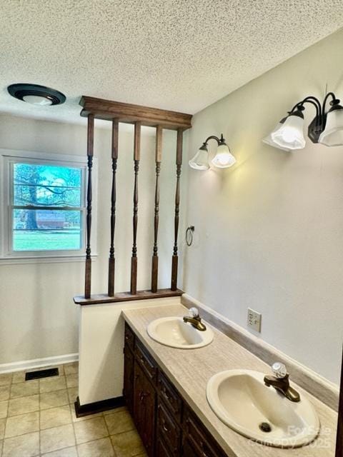 127 Edgeway Rd, Mooresville, NC 28117 - bathroom featuring a textured ceiling, double vanity, tile patterned floors, and baseboards