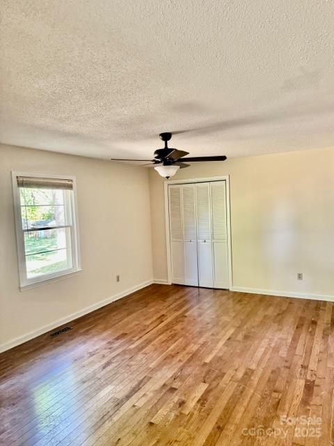 127 Edgeway Rd, Mooresville, NC 28117 - unfurnished bedroom featuring light wood finished floors, a textured ceiling, baseboards, a ceiling fan, and a closet