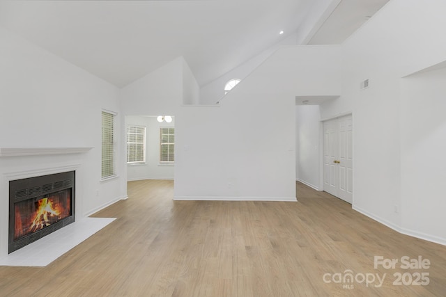 6523 Clavell Ln Unit I, Charlotte, NC 28210 - unfurnished living room with baseboards, a warm lit fireplace, wood finished floors, and high vaulted ceiling