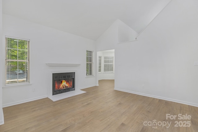 6523 Clavell Ln Unit I, Charlotte, NC 28210 - unfurnished living room featuring a fireplace with flush hearth, light wood-style floors, high vaulted ceiling, and baseboards