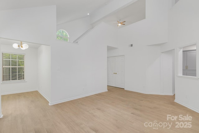 6523 Clavell Ln Unit I, Charlotte, NC 28210 - empty room with light wood finished floors, visible vents, baseboards, high vaulted ceiling, and ceiling fan with notable chandelier