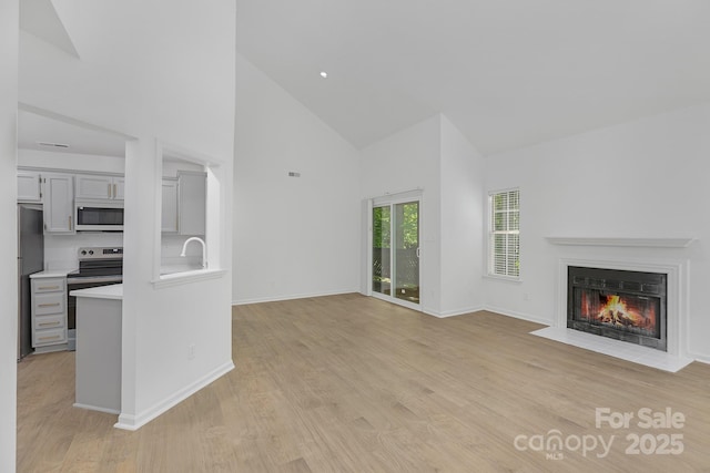 6523 Clavell Ln Unit I, Charlotte, NC 28210 - unfurnished living room with a fireplace with flush hearth, light wood-style flooring, baseboards, and high vaulted ceiling