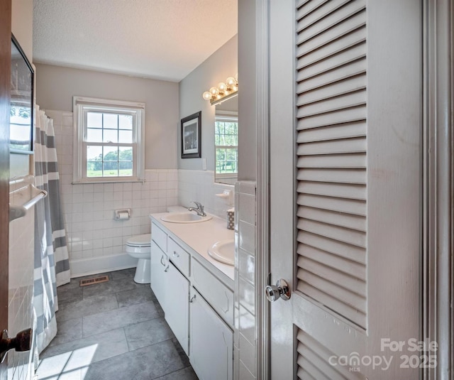 153 Coachman Loop, Statesville, NC 28625 - bathroom featuring toilet, tile walls, double vanity, tile patterned floors, and a wainscoted wall