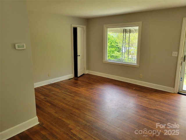 unfurnished room featuring baseboards and dark wood-style flooring