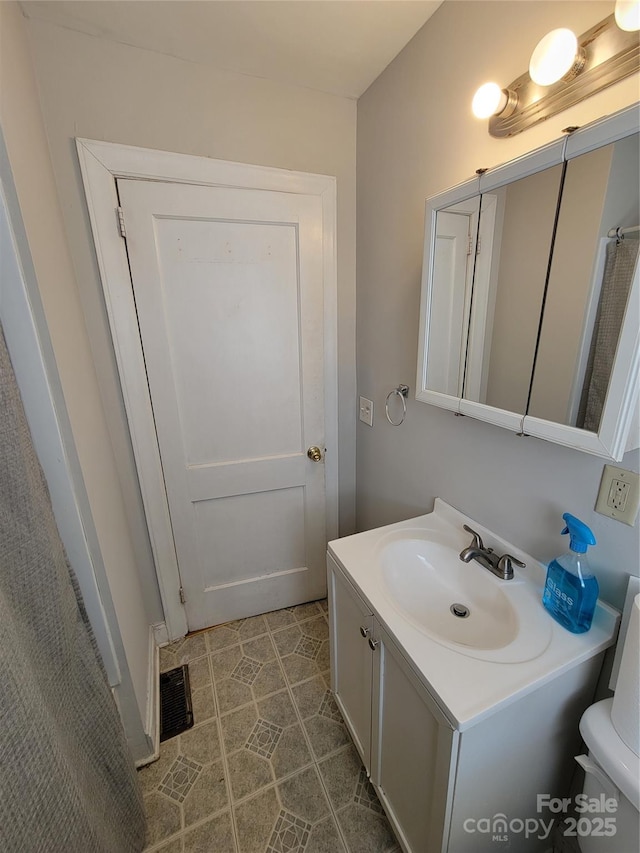 bathroom featuring tile patterned flooring, visible vents, toilet, and vanity