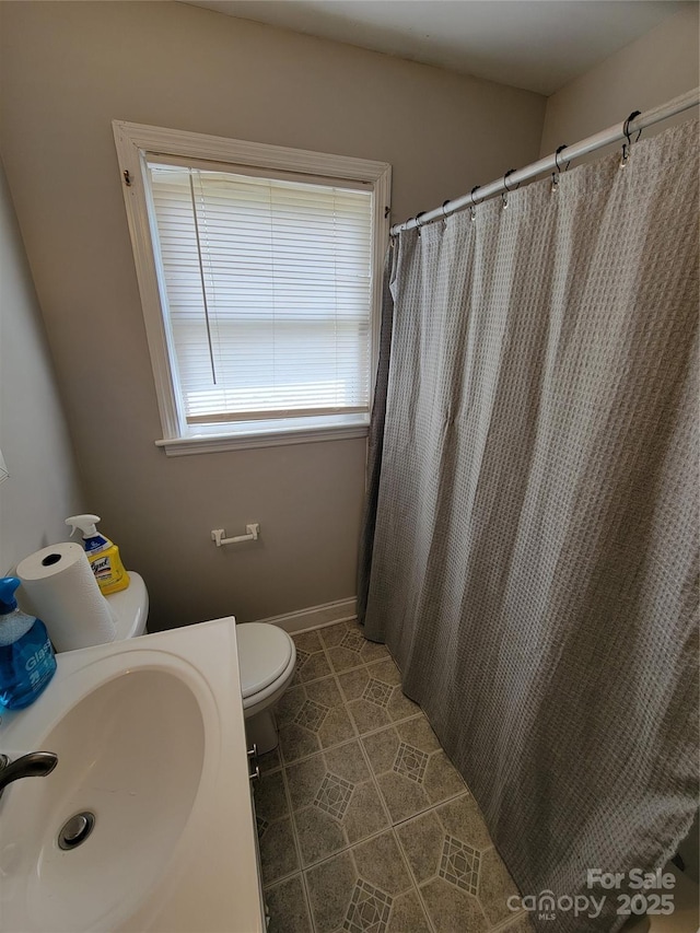 bathroom with a shower with curtain, tile patterned floors, toilet, and a sink