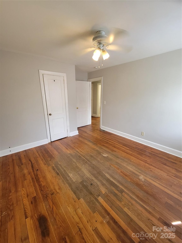 unfurnished room with a ceiling fan, baseboards, and dark wood finished floors