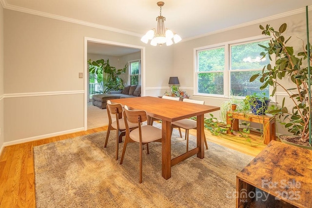 dining space with a chandelier, ornamental molding, baseboards, and light wood-type flooring