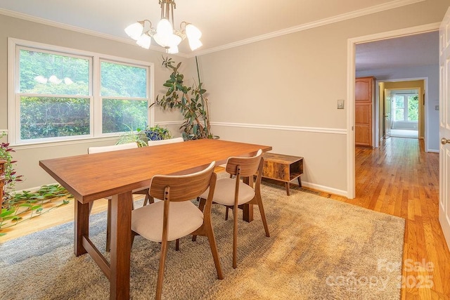 dining space featuring an inviting chandelier, ornamental molding, baseboards, and light wood finished floors