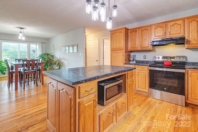 kitchen featuring appliances with stainless steel finishes, a textured ceiling, under cabinet range hood, dark countertops, and light wood-type flooring