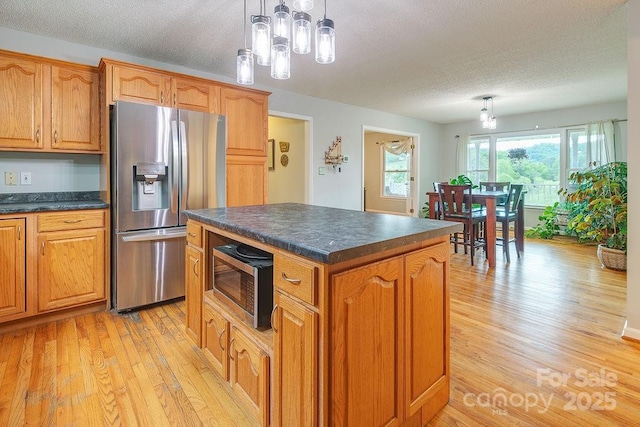 kitchen with dark countertops, a textured ceiling, stainless steel appliances, and light wood-style flooring