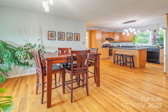 dining room with an inviting chandelier, a textured ceiling, and light wood-style flooring