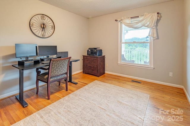 office space with baseboards, visible vents, a textured ceiling, and wood finished floors