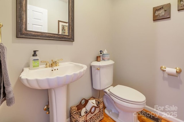 bathroom featuring toilet, visible vents, baseboards, and a sink