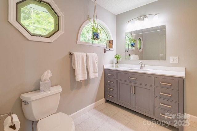 bathroom featuring baseboards, vanity, and toilet