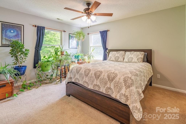 carpeted bedroom with a textured ceiling, visible vents, baseboards, and a ceiling fan