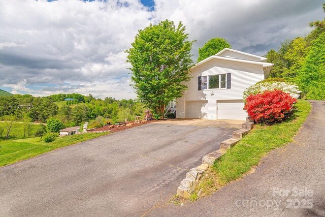 view of side of home featuring an attached garage and driveway