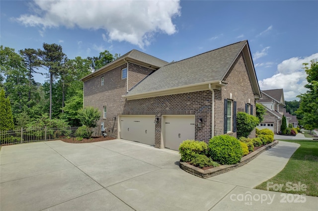 view of side of home featuring roof with shingles, fence, driveway, and brick siding