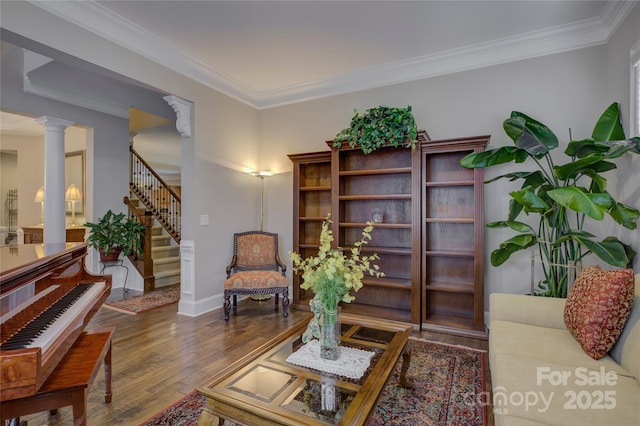 sitting room featuring crown molding, decorative columns, stairs, and wood finished floors