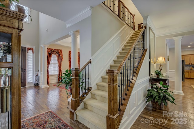 entrance foyer featuring stairway, a decorative wall, ornamental molding, and decorative columns
