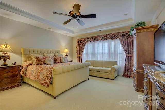 bedroom with visible vents, ornamental molding, a tray ceiling, and light colored carpet