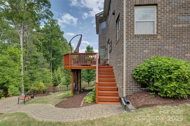 exterior space featuring brick siding, stairs, and a deck