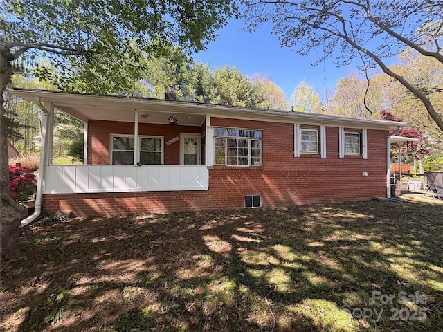 exterior space with brick siding, a front yard, and covered porch