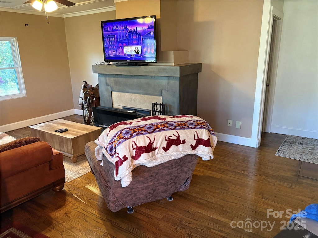 bedroom with a ceiling fan, crown molding, wood finished floors, a fireplace, and baseboards