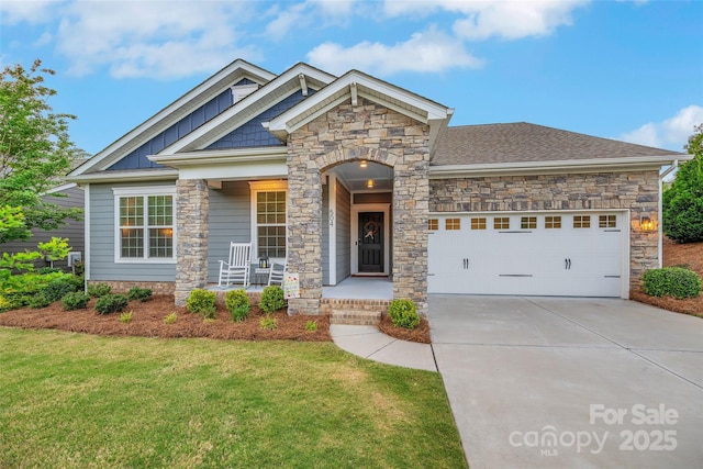 craftsman-style house with a porch, a garage, a front lawn, concrete driveway, and stone siding