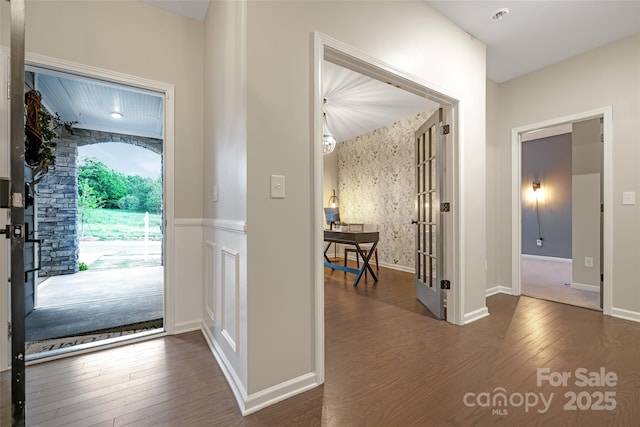entrance foyer featuring french doors, wood finished floors, and a wainscoted wall