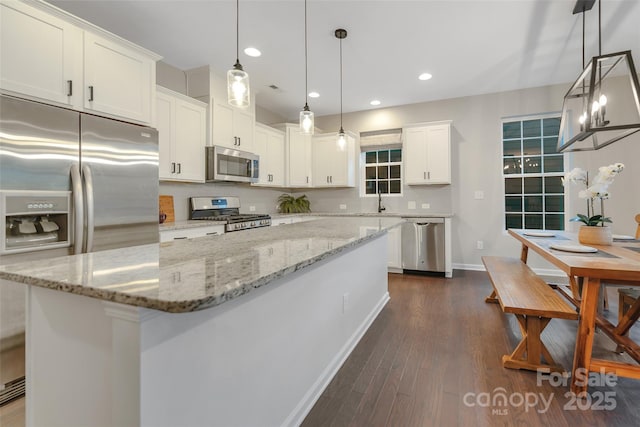 kitchen with a kitchen island, baseboards, white cabinets, stainless steel appliances, and dark wood-type flooring