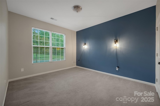 unfurnished room with baseboards, visible vents, and carpet