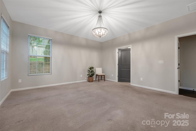 carpeted spare room featuring an inviting chandelier, baseboards, and visible vents
