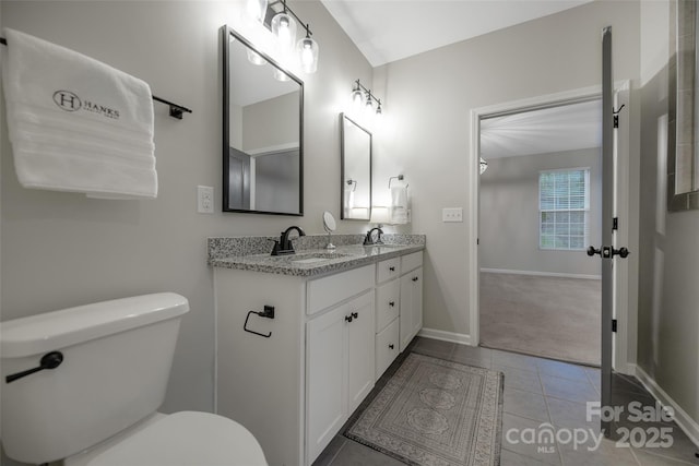 full bath with double vanity, toilet, baseboards, and a sink