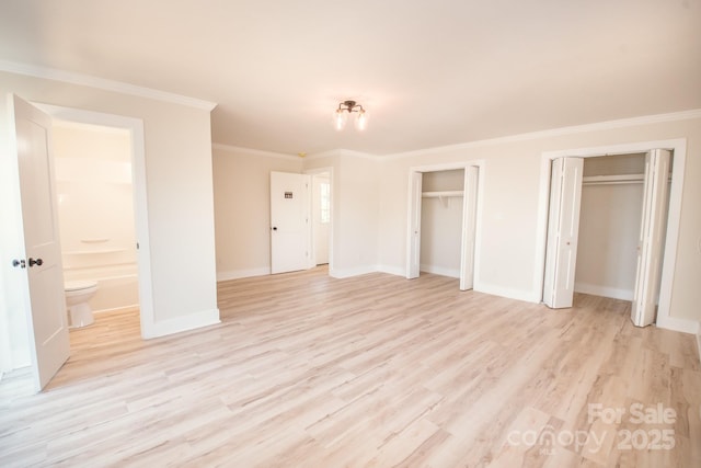 451 S Strand Dr, Norwood, NC 28128 - unfurnished bedroom with light wood finished floors, multiple closets, baseboards, and ornamental molding