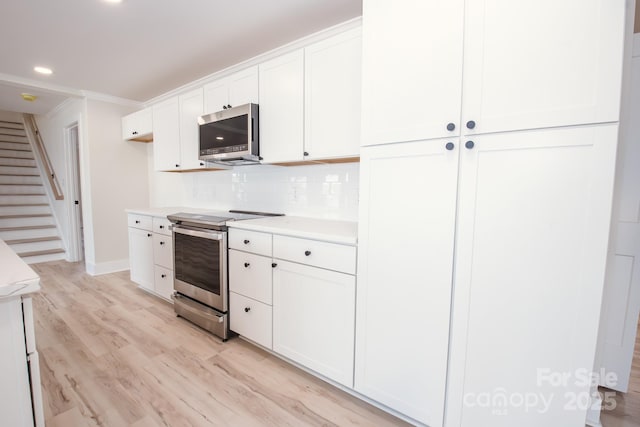 451 S Strand Dr, Norwood, NC 28128 - kitchen featuring white cabinets, light countertops, light wood-type flooring, baseboards, and appliances with stainless steel finishes