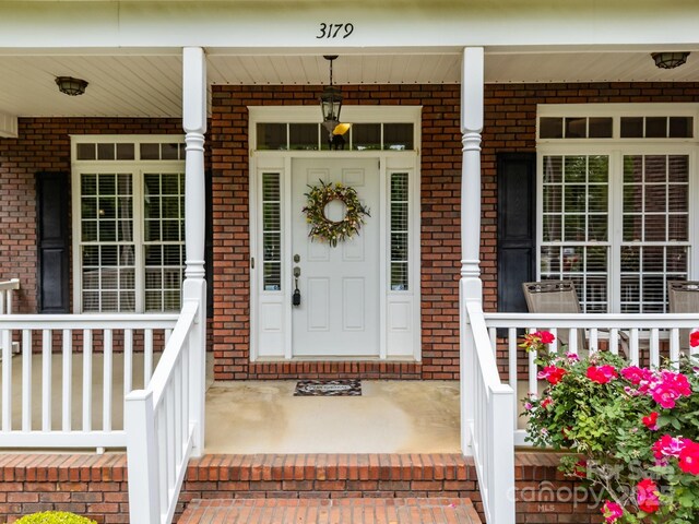 property entrance with a porch and brick siding