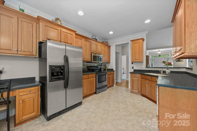 kitchen featuring crown molding, brown cabinets, dark countertops, appliances with stainless steel finishes, and a sink