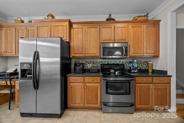 kitchen with ornamental molding, appliances with stainless steel finishes, brown cabinets, and dark countertops