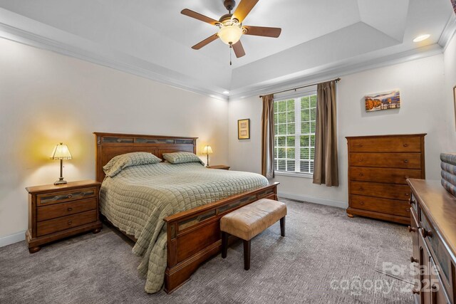 carpeted bedroom with recessed lighting, a tray ceiling, ornamental molding, and baseboards