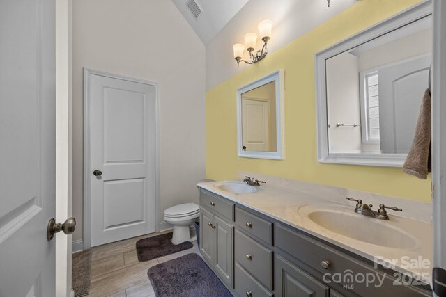 bathroom featuring double vanity, visible vents, a sink, and vaulted ceiling