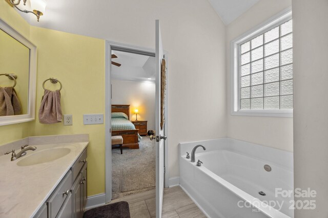 bathroom with a garden tub, baseboards, ensuite bath, and vanity